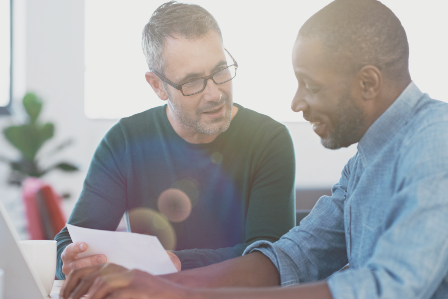 Stock image of two men in an office looking at a document.