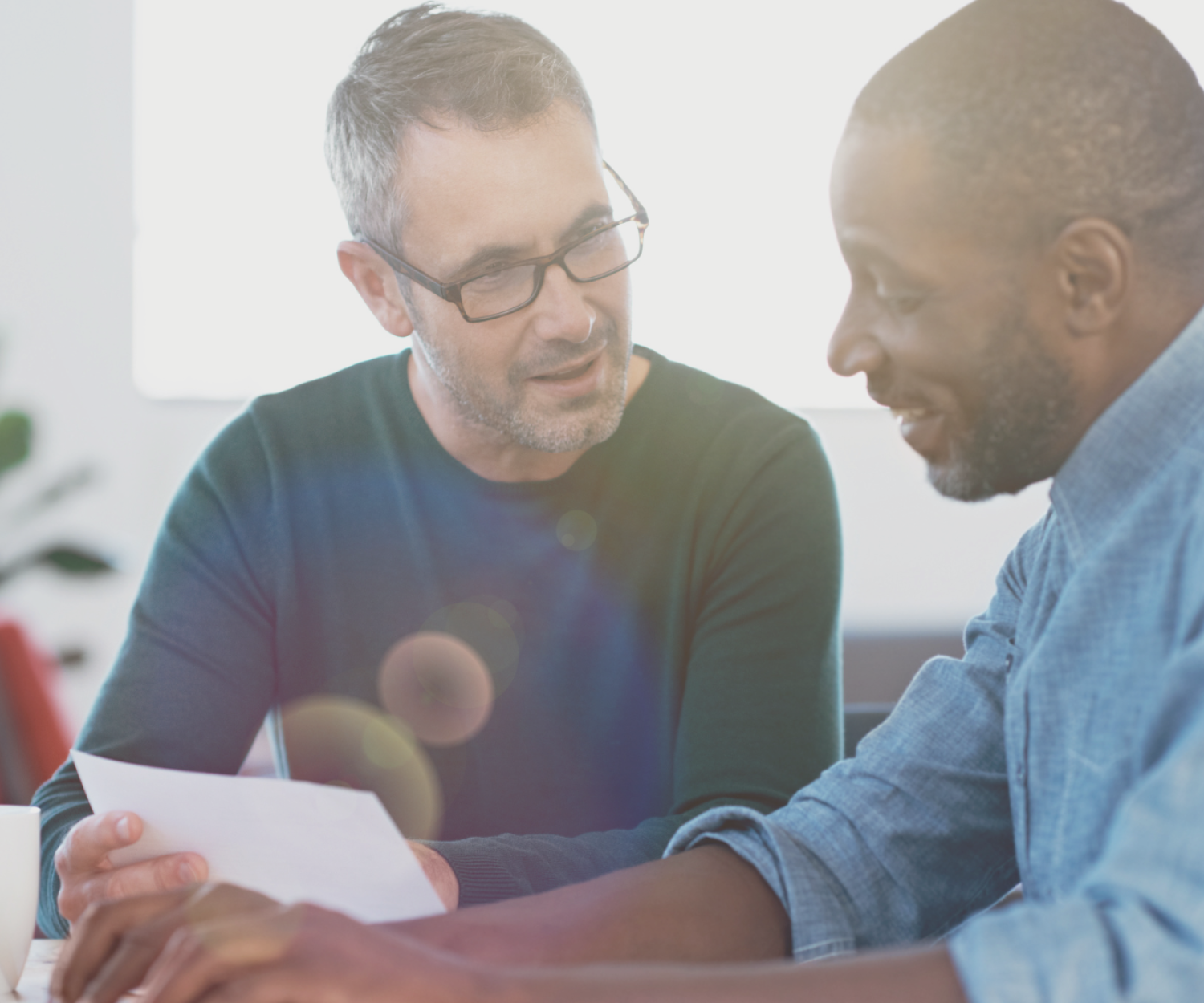 Stock image of two men in an office looking at a document.